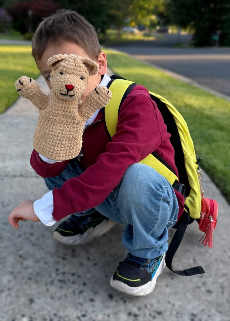 Young boy dressed as Mister Rogers holding a handmade crochet classic Daniel Striped Tiger puppet