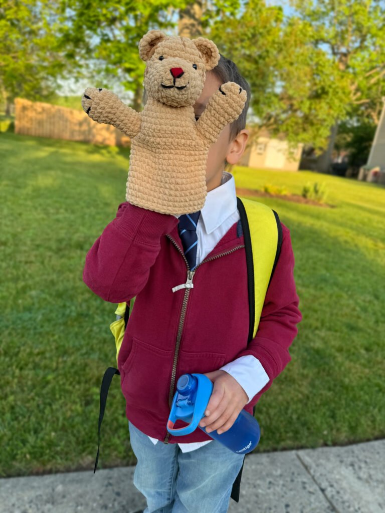 Young boy dressed as Mister Rogers holding a handmade crochet classic Daniel Striped Tiger puppet